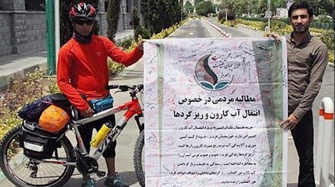 راکب دراجة هوائية من أهالي خوزستان يحمل عريضة تضم تواقيع المعترضين علی نقل مياه کارون وعلی ذرات الغبار، مقابل برلمان النظام